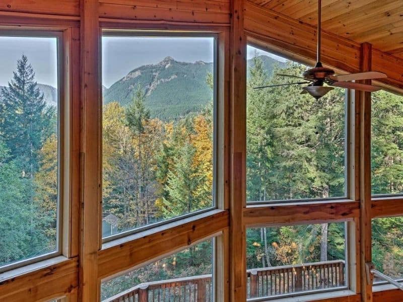 View from a large cabin rental near Mt Rainier with huge windows looking over forest with mountain views.