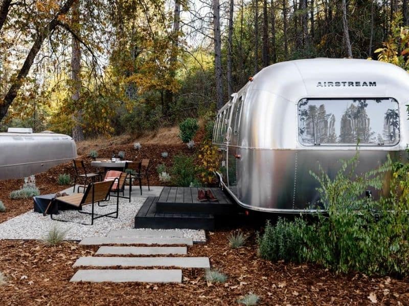 Exterior view of an airstream trailer at AutoCamp Yosemite with outdoor patio and dining area.