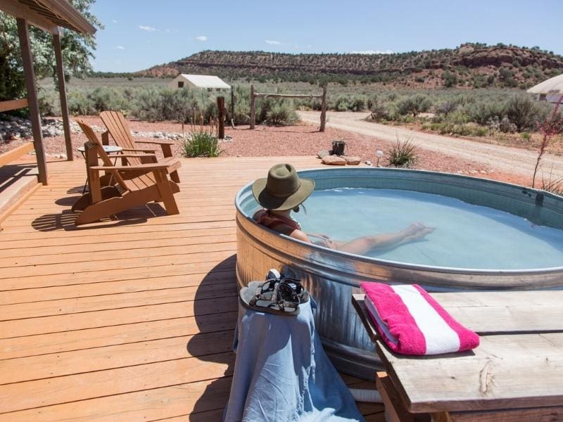Person soaking in an outdoor hot tub at Basecamp 39 - a glamping site near Zion National Park