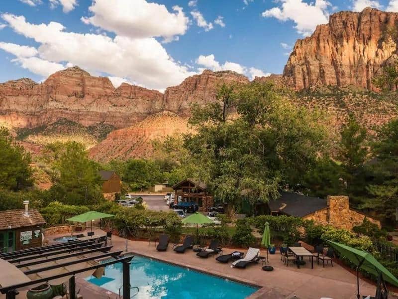 Pool and loungers at Flanigan's Inn against Zion National Park's red rock canyons.