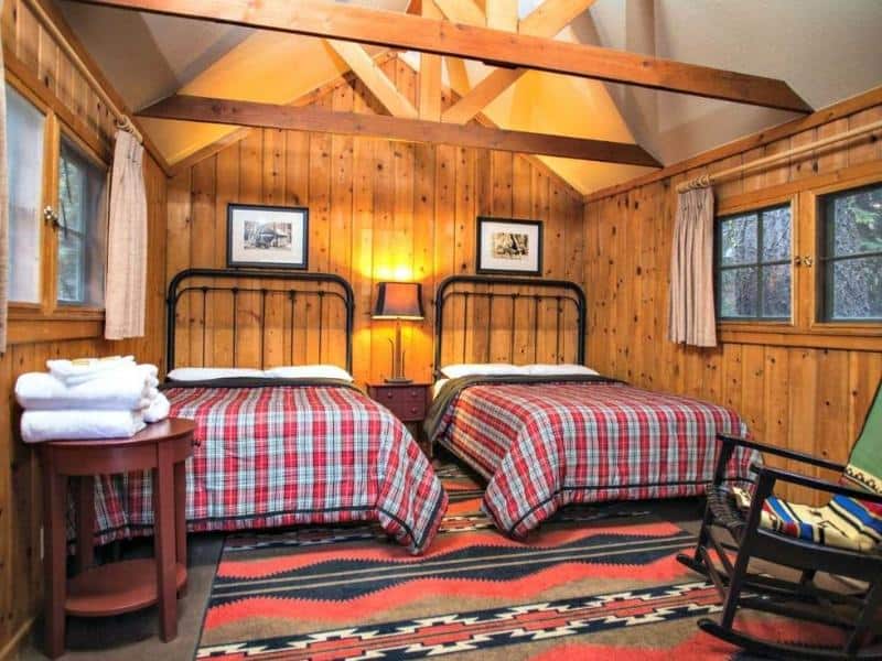 Interior of a cabin at Grant Grove Cabins showing two beds with red checkered bedding and wood-paneled walls, a popular option for Kings Canyon / Sequoia lodging.