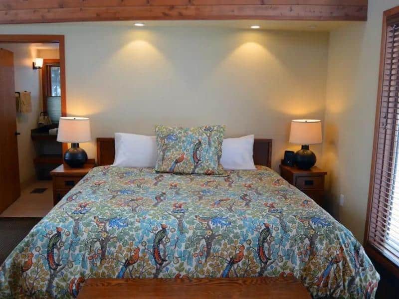 A warmly lit room at Montecito Sequoia Lodge with a queen bed covered in a floral bedspread.