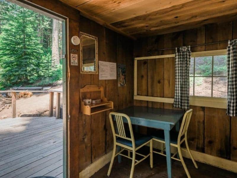 Rustic screened-in porch of a cabin at Silver City Mountain Resort with a simple table and chairs, a lesser known accommodation in the Mineral King section of Sequoia National Park.