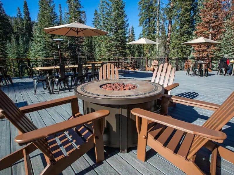 Outdoor patio at Wuksachi Lodge with a central fire pit, surrounded by wooden Adirondack chairs. The most upscale lodging option in Sequoia National Park.