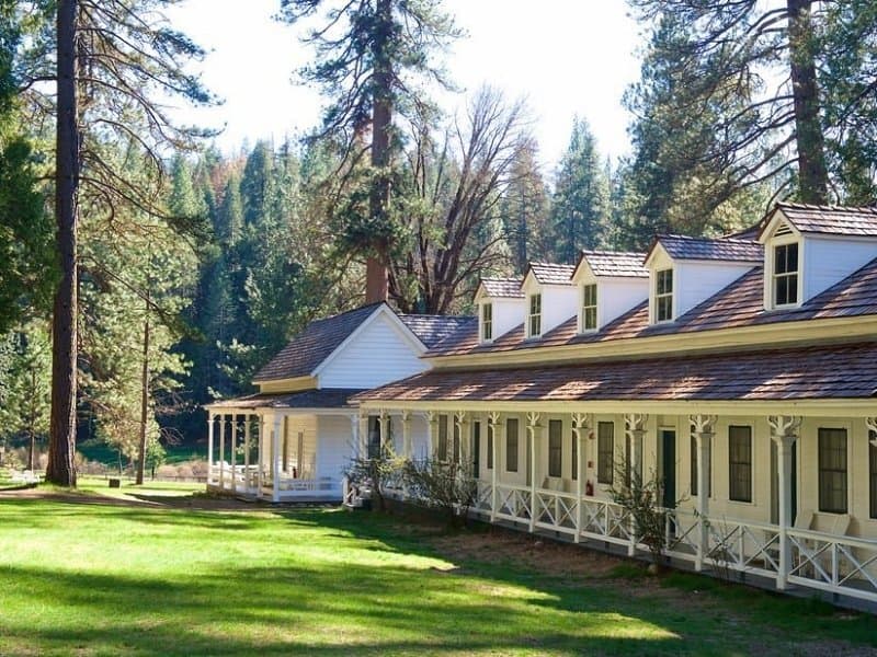Exterior view of Wawona Hotel in Yosemite with lawn and trees.