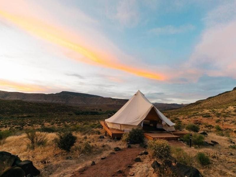 Exterior view of glamping site at Zion Wildflower in Virgin UT with large canvas tent on a wooden deck