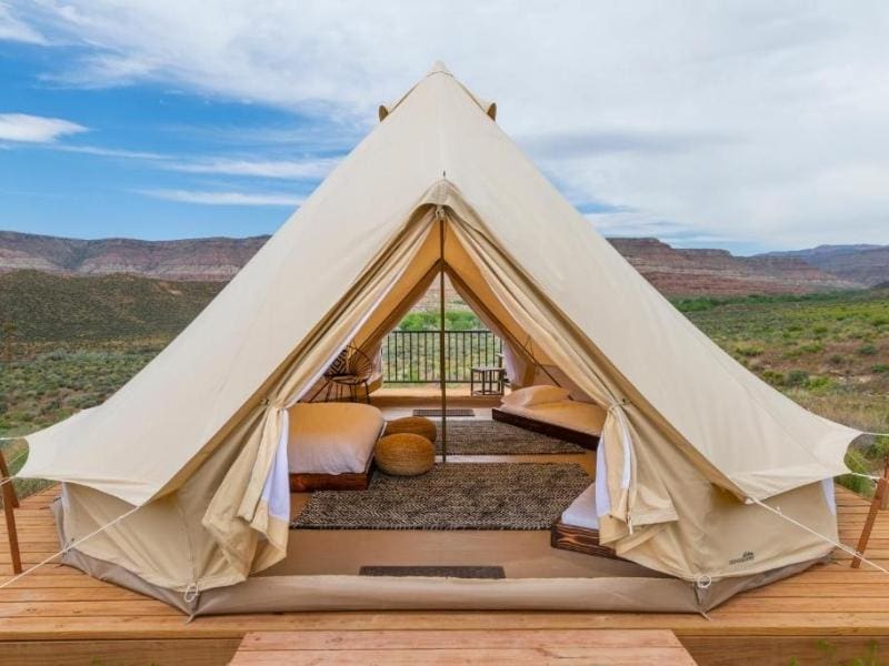 Large canvas glamping tent at Zion Wildflower on wooden deck with bed and large floor rug