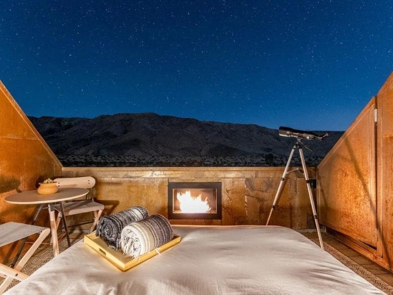Glamping in Joshua Tree at Desert Saga Tiny Home. Open rooftop bed with fireplace, telescope and table.