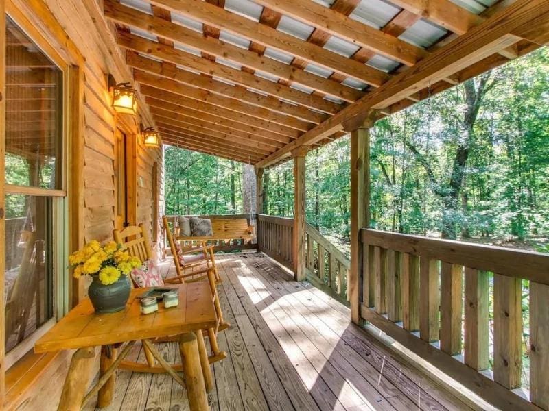 Large wooden porch overlooking wooded area at Pigeon Forge cabin Vrbo listing