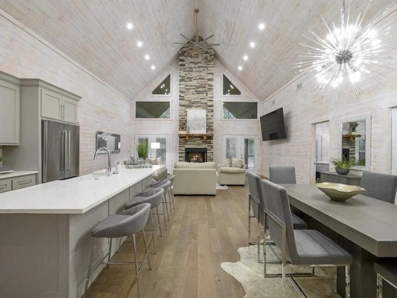 Spacious living and kitchen area with high ceilings, modern furnishings, and a unique light fixture, found in a high-end Broken Bow Vrbo rental.