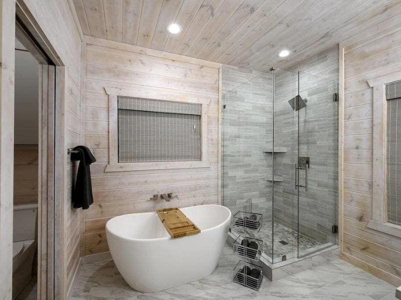 Elegant bathroom in 'Mystic Love' Broken Bow cabin, featuring a freestanding tub and glass-enclosed shower with grey tile.