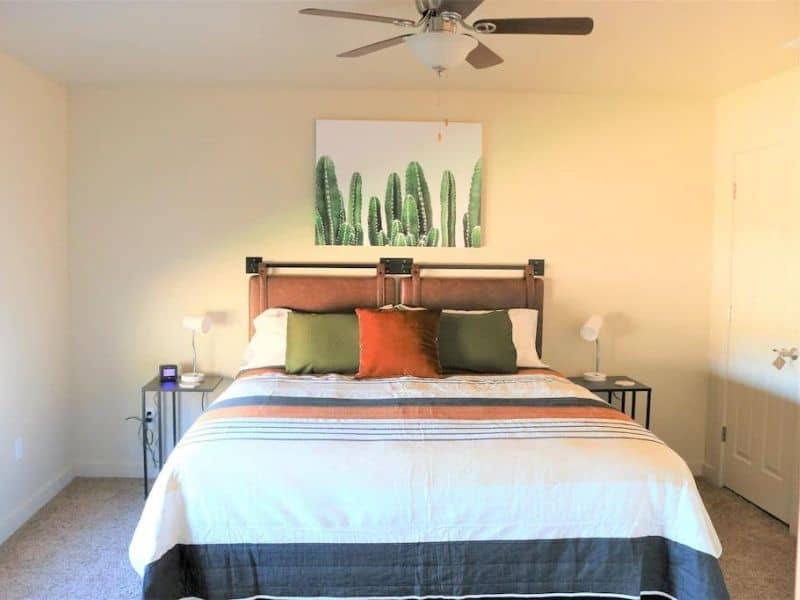 Cozy bedroom setup in a Moab rental featuring a bed with a cactus print headboard, capturing the essence of the desert.