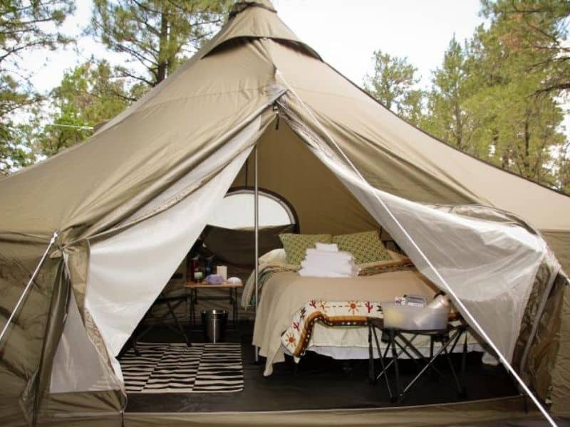 Open canvas glamping text with bed and nightstand inside. Arizona Luxury Expeditions Grand Canyon Glamping.