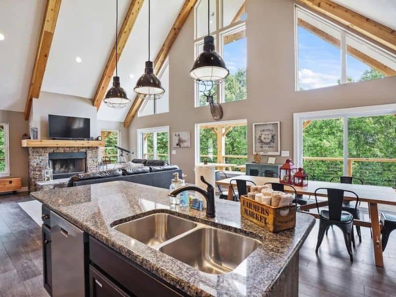 Upscale kitchen and main living area with high vaulted ceilings and large windows at luxury cabin rental in Hocking Hills