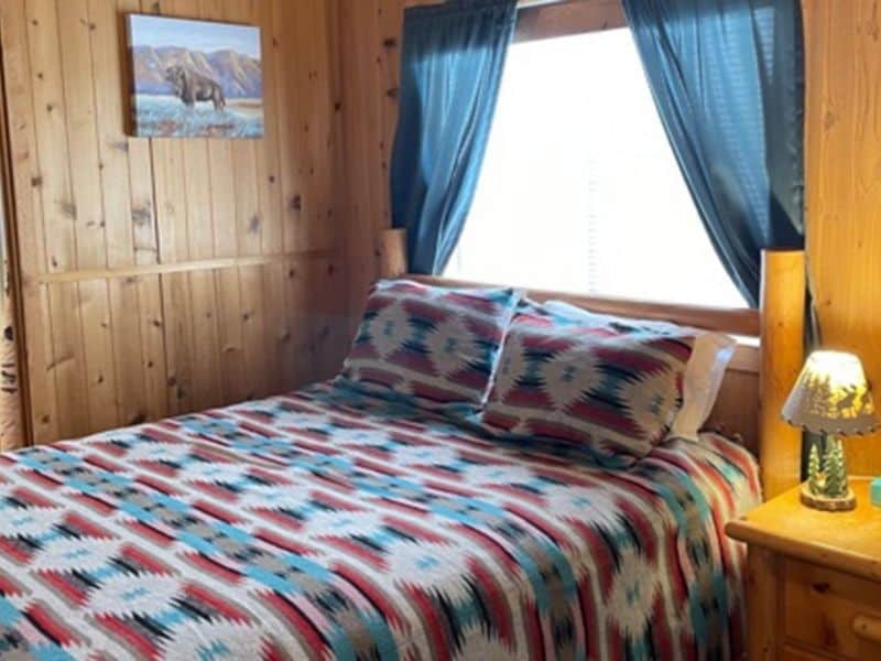 Interior of rustic cabin at Kaibab Lodge with queen bed and colorful aztec style bedding