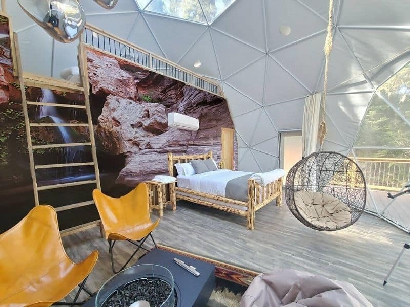 Themed dome suite at Clear Sky Resorts Grand Canyon with bird cage hanging chair, king bed, loft, and seating area
