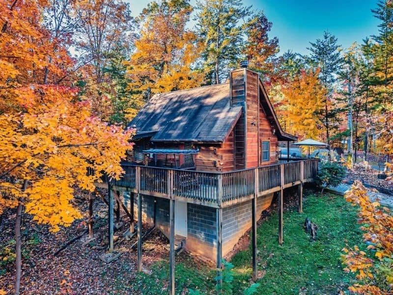 Exterior of a traditional wood cabin amongst autumn foliage in Pigeon Forge, Tenneessee
