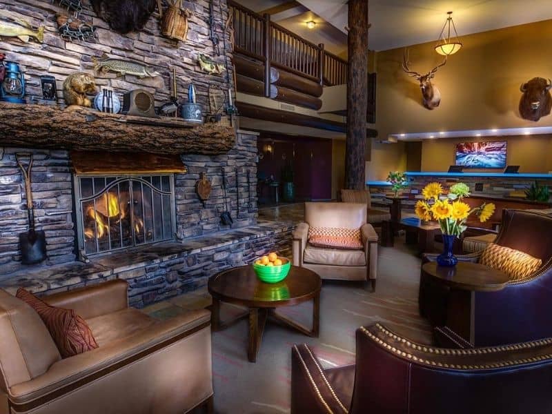 Rustic guest reception at The Grand Hotel Grand Canyon with large stone fireplace and leather armchairs