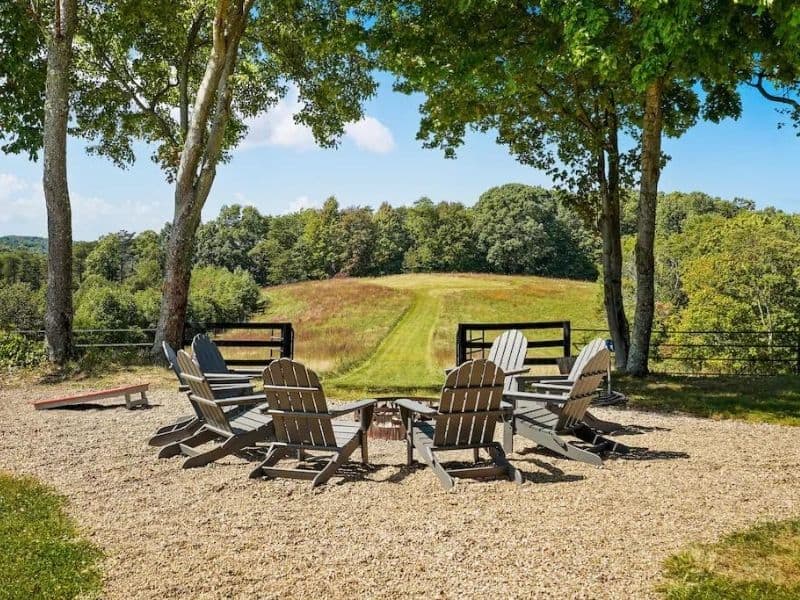 Adirondack chairs around a fire pit overlooking grass and woodlands at 5-bedroom luxury cabin in Hocking Hills