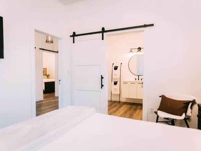 A glimpse from the bed into a well-appointed bathroom with sleek fixtures and tasteful decor in a private room of a luxury cabin in Hocking Hills.