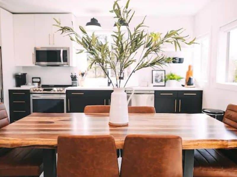 Modern dining space with a large wooden table and sleek kitchen amenities.