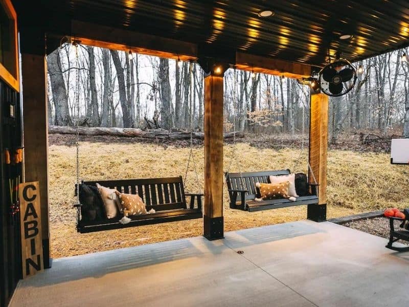Relaxing covered patio area with swing benches and throw pillows at a Hocking Hills cabin rental.
