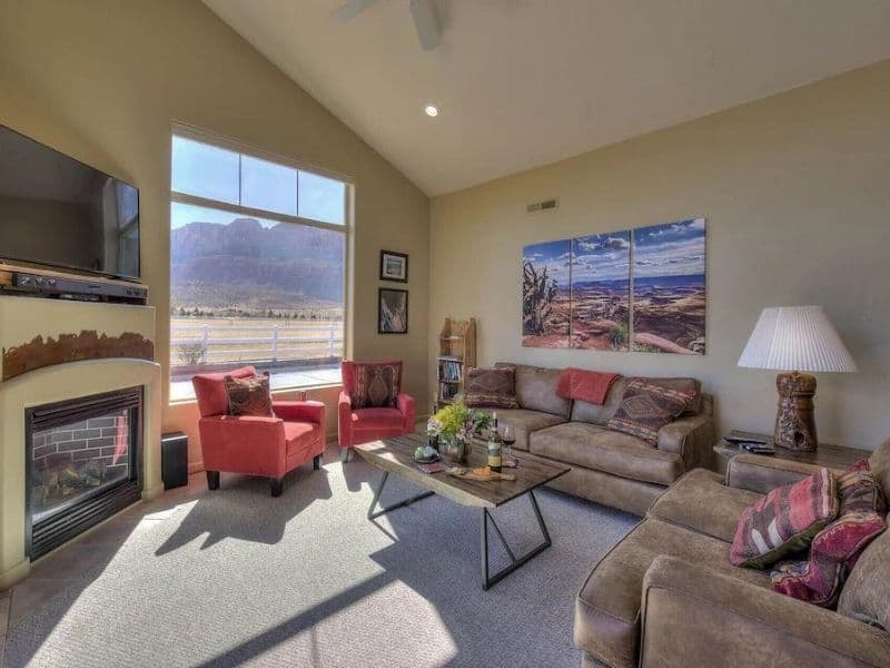 Living room in Laughing Labs, a Moab Vrbo with comfortable seating, a fireplace, and a large window with mountain views.