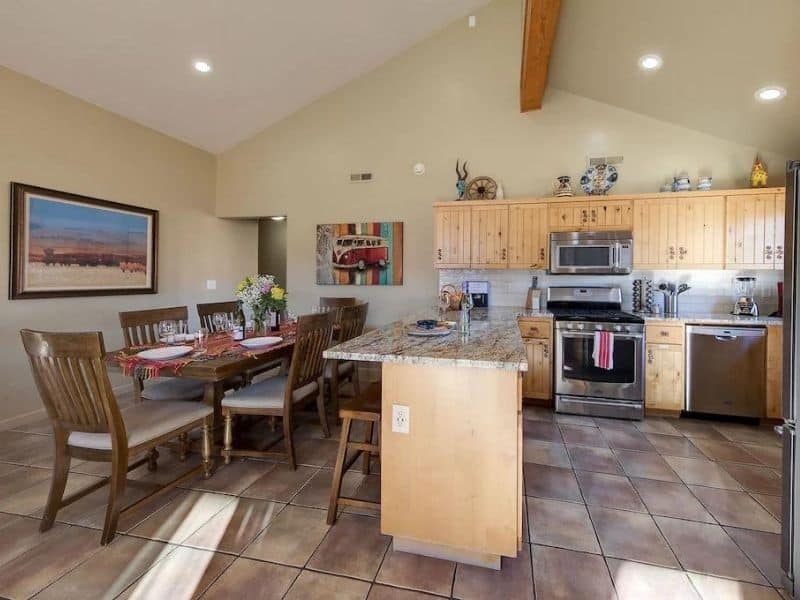 Dining area and kitchen with wooden cabinetry and a tiled floor in a vacation rental in Moab.
