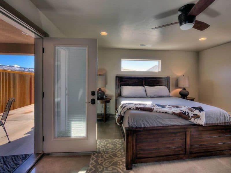 A well-lit bedroom with a large bed and sliding glass door leading to a patio in a Moab Airbnb.