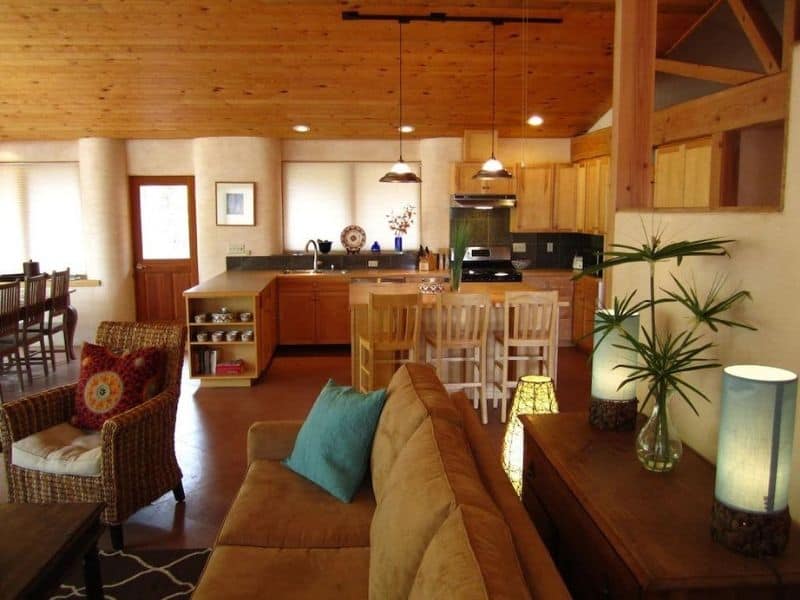 Spacious and well-lit living area with a wooden ceiling and kitchenette, part of a Moab eco vacation rental.