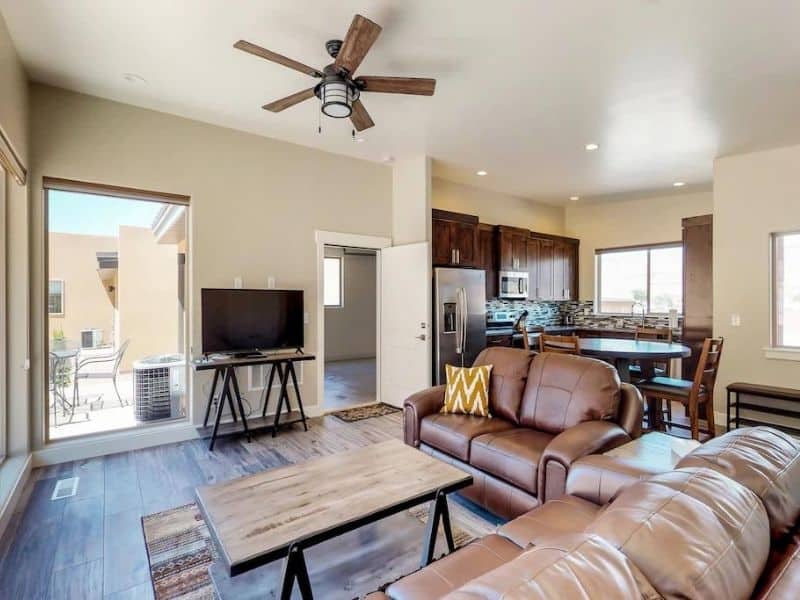 Spacious living room with modern amenities and ample seating, with a large window that looks out to Moab's natural beauty.