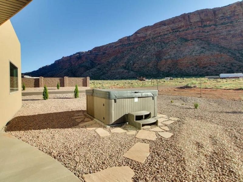 Private outdoor hot tub with scenic views of Moab's rugged cliffs at a Moab Airbnb.