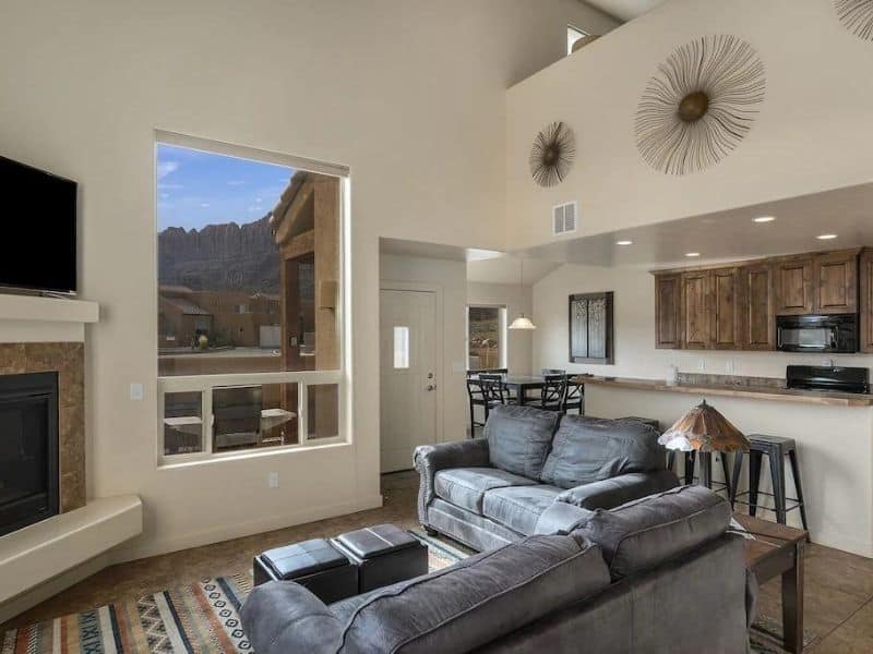 Spacious living area with a large window framing Moab's unique rock formations, part of an Airbnb.