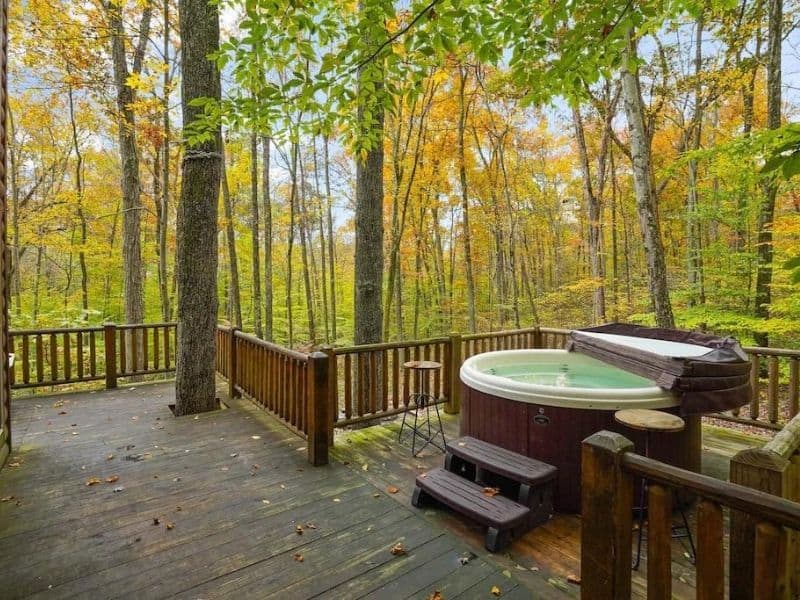 Private hot tub on a wooden deck surrounded by the vibrant trees at a cabin rental in Hocking Hills, OH.