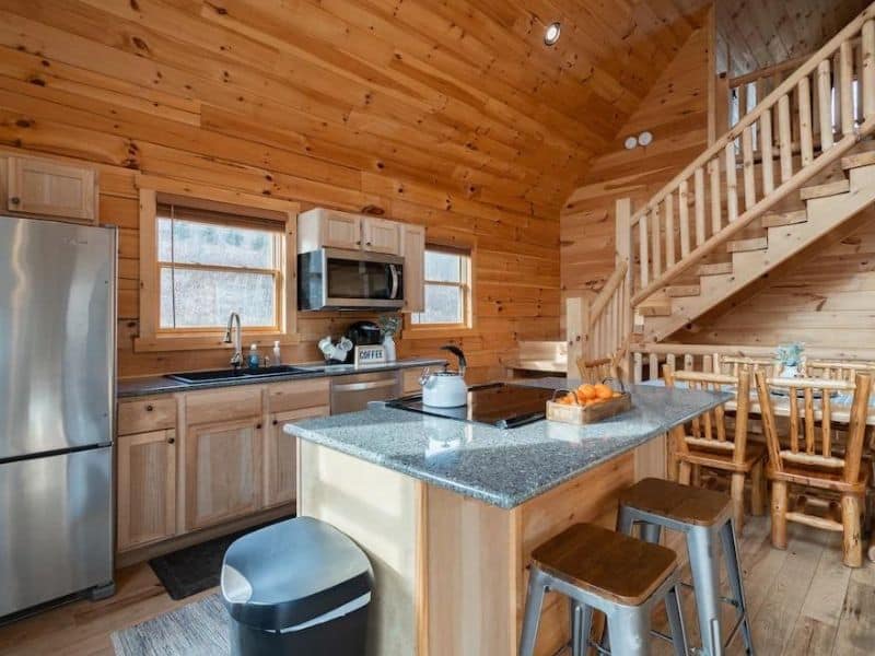 Modern kitchen in a Hocking Hills log cabin featuring stainless steel appliances and a wooden dining area.