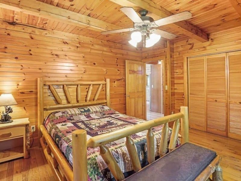 Rustic charm meets comfort in this Hocking Hills cabin bedroom, with a crafted wooden bed and warm lighting.