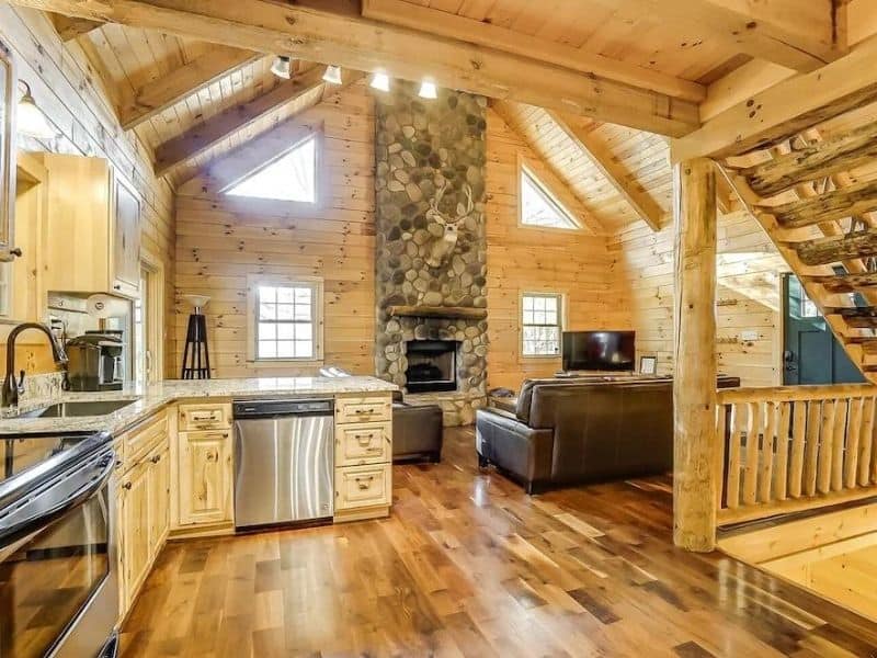 Interior of Whitetail Pines cabin featuring a high ceiling with wooden beams and a stone fireplace; a luxury cabin rental in Hocking Hills.