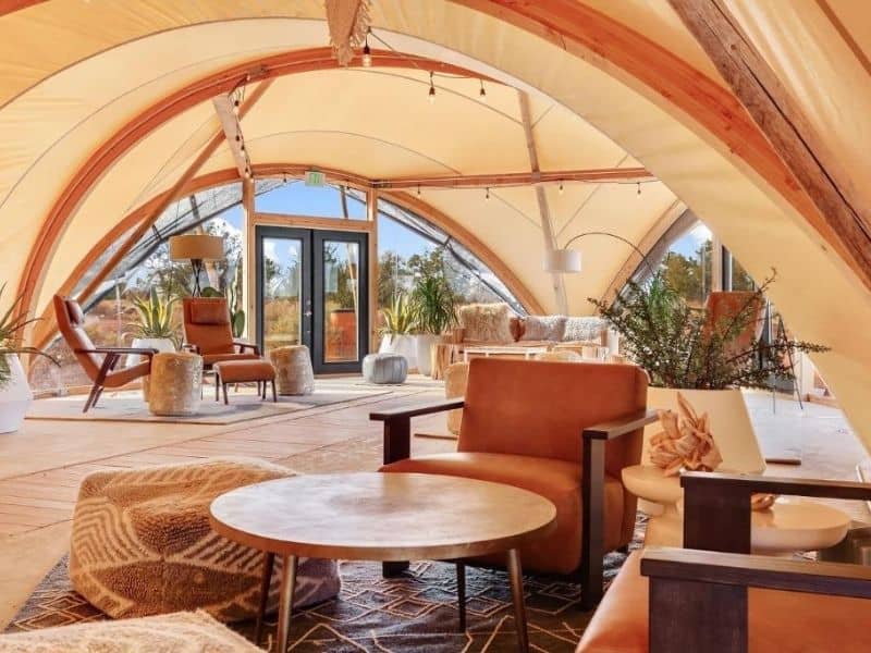 Tented guest reception area at Under Canvas Grand Canyon with leather seats, fabric footrests, and coffee tables