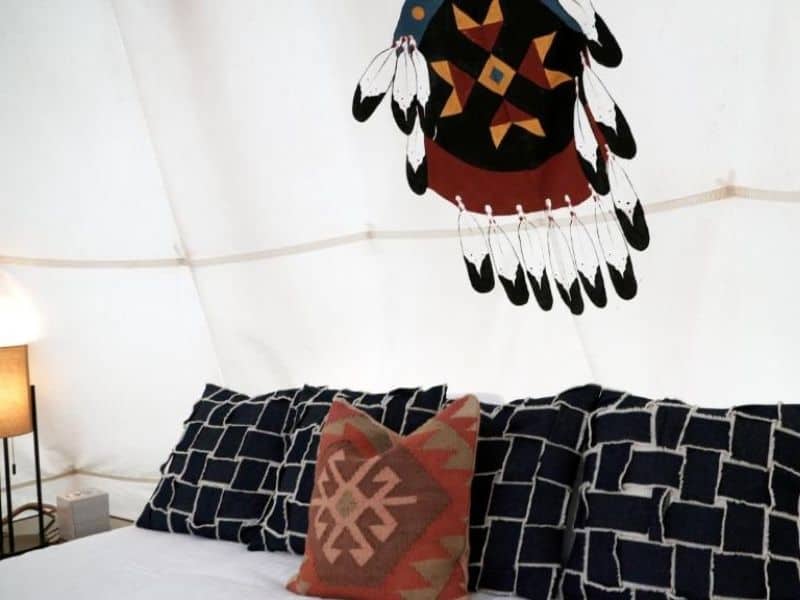 Bed with Native American dream catcher hanging above it in a tipi at Dreamcatcher Tipi Hotel in Gardiner, Montana