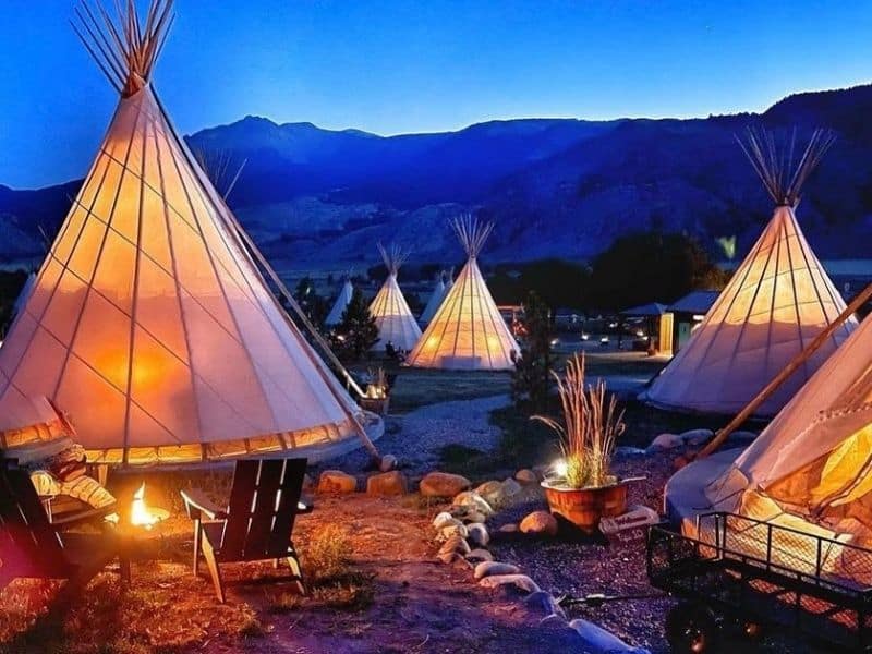 Several tipis lit up at dusk at Dreamcatcher Tipi Hotel in Gardiner, MT. Luxury glamping near Yellowstone's North Entrance