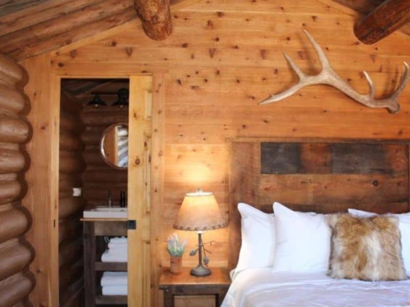 Rustic wood room interior at Elkhorn Cabins and Inn in West Yellowstone with antlers hanging above the bed
