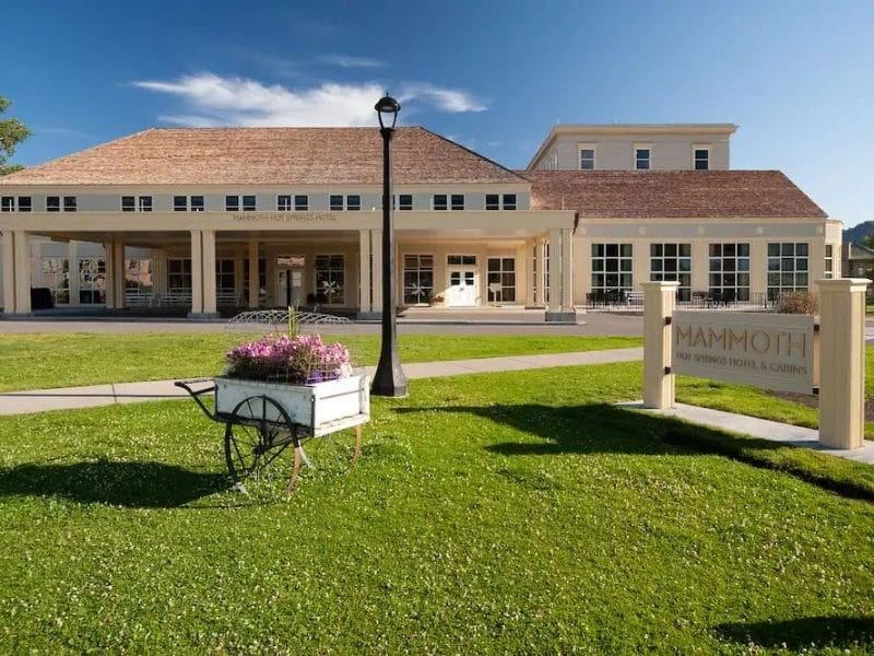Exterior entrance to Mammoth Hot Springs Hotel and Cabins in Yellowstone with large green lawn