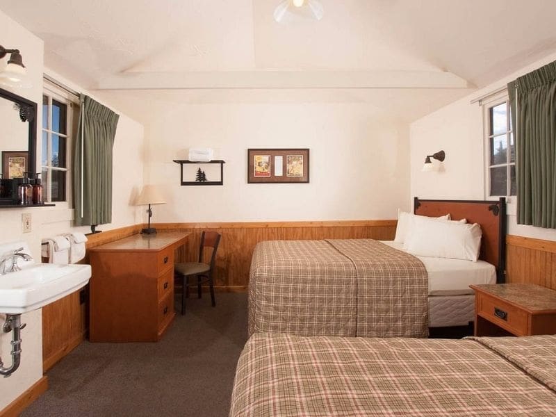 Simple interior of rustic cabin at Old Faithful Lodge Cabins in Yellowstone with two queen beds and a desk