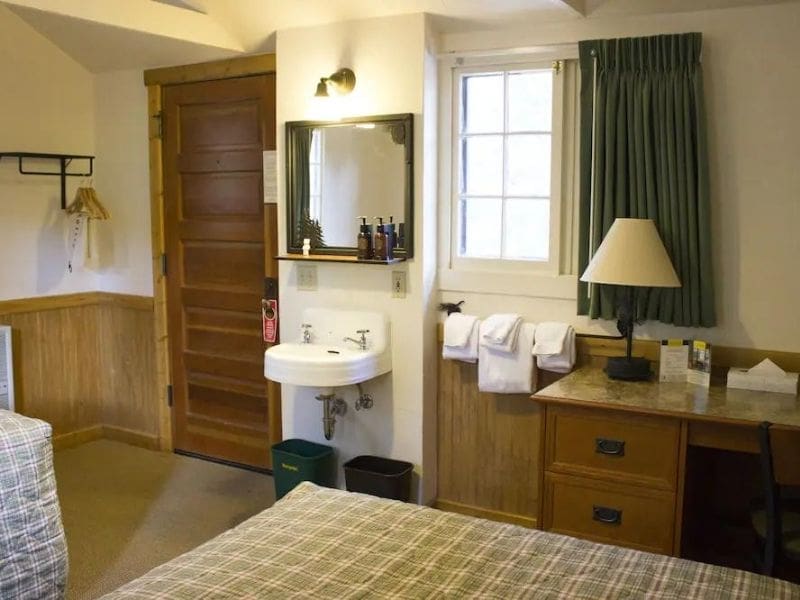 Interior of basic cabin at Old Faithful Lodge Cabins with bed, nightstand, and sink.