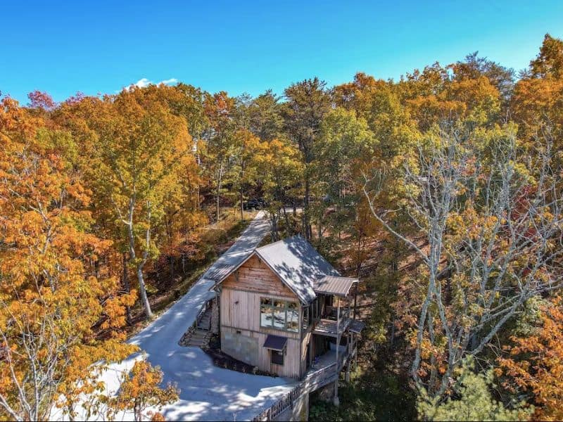 Exterior of Pigeon Forge cabin rental with classic wood panel construction and balcony. Surrounded by forest.