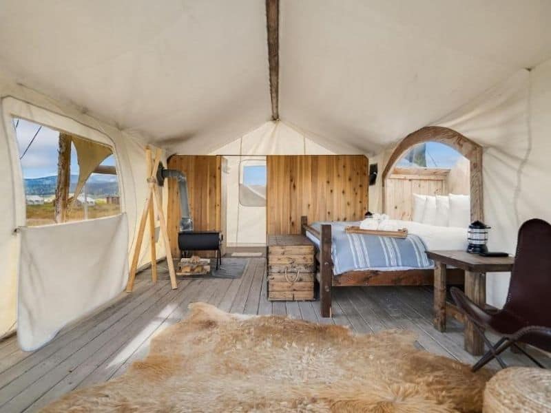 View inside a canvas glamping tent at Under Canvas West Yellowstone with king bed and ensuite bathroom