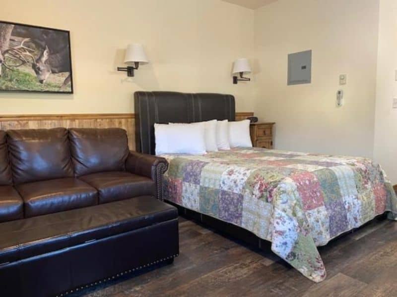 Interior of a cottage at Yellowstone Riverside Cottages in Gardiner MT, with queen bed and leather couch