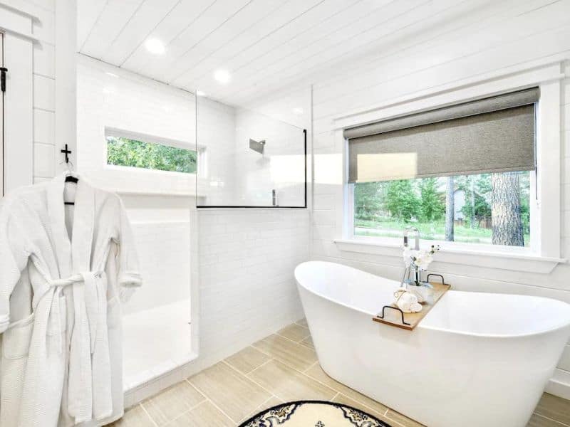 Elegant bathroom in a luxury cabin in Broken Bow with a freestanding bathtub, walk-in shower, and a plush white robe hanging.