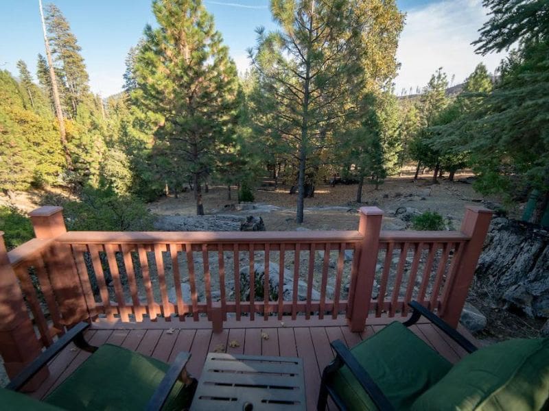 Outdoor deck with seating, offering a view of the forest at a Vrbo cabin near Yosemite.
