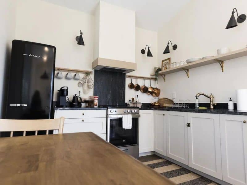 Well-equipped kitchen in a Hocking Hills cottage rental for 2, complete with a classic black refrigerator, white cabinetry, and stylish open shelving.